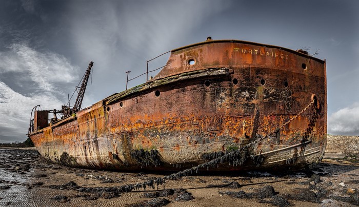 Abandoned rusty shipwreck named Portlairge on a muddy shore