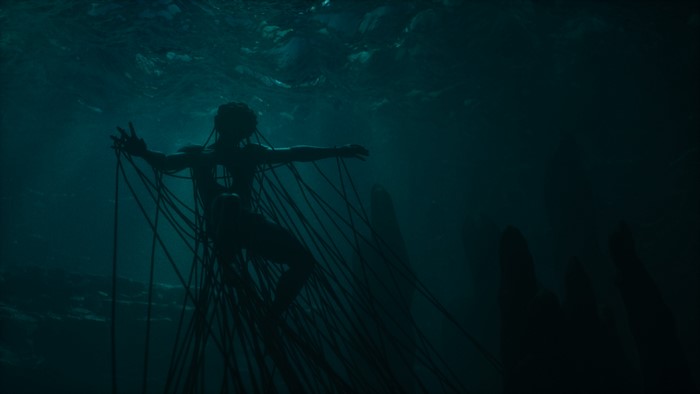 Silhouette of a person underwater connected by wires