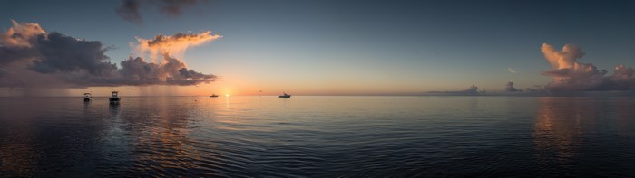 Panoramic sunset over the sea with boats and clouds
