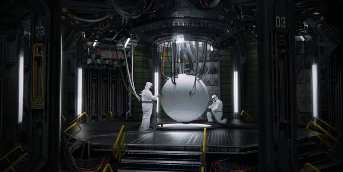 Scientists in clean suits working on a large sphere in a futuristic lab