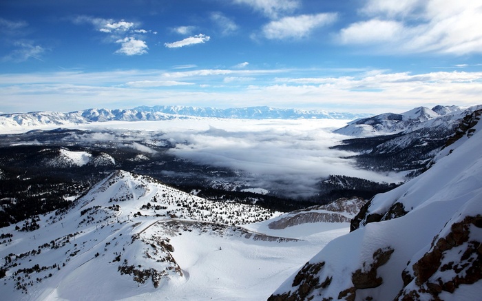 Snowy mountain range with clouds and blue sky
