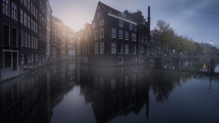 Amsterdam canal with buildings and mist in the morning