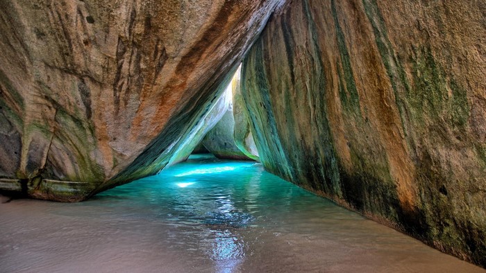 Cave entrance with turquoise water and large boulders