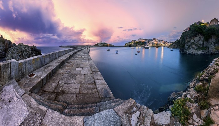 Stone pier and harbor at sunset with colorful clouds
