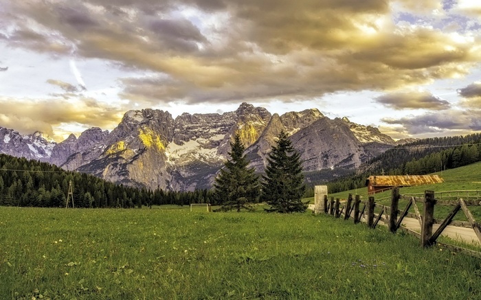 Mountain range with green meadow and wooden fence