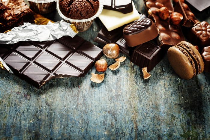 Assortment of chocolates, brownies, and macarons on a wooden surface