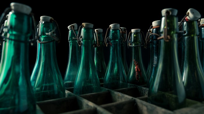 Green glass bottles with swing tops in a wooden crate