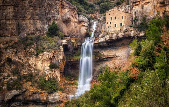 Monastery built into a cliff face with a waterfall