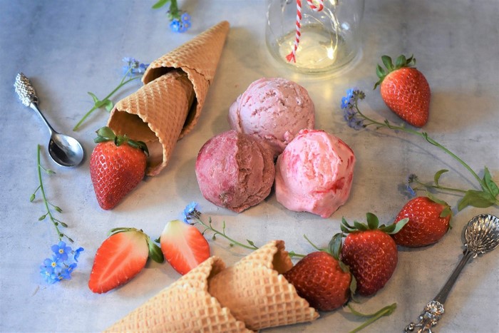 Strawberry ice cream scoops with cones and fresh strawberries