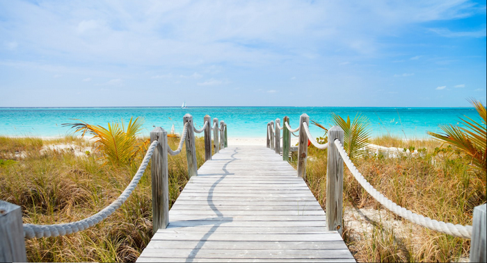 Wooden boardwalk leading to a tropical beach and ocean