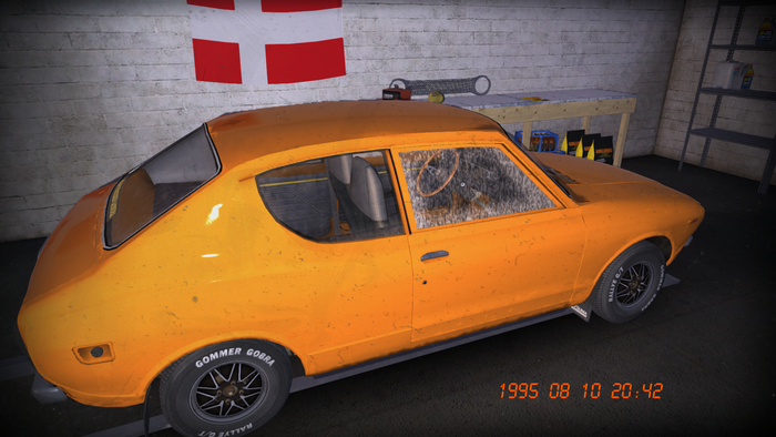 Orange car in a garage with Danish flag