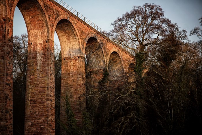 Stone viaduct bridge with arches and trees
