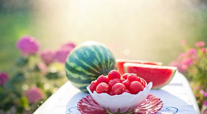 Watermelon and berries on a table with flowers
