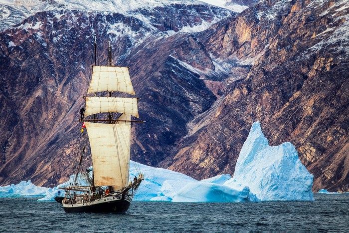 Sailing ship near icebergs and mountains in Greenland