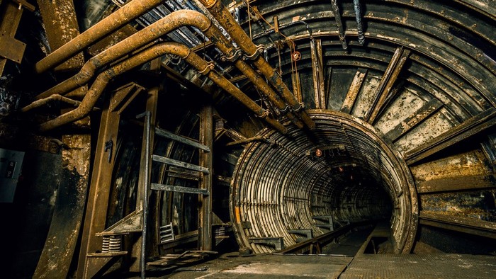 Abandoned underground tunnel with rusty pipes