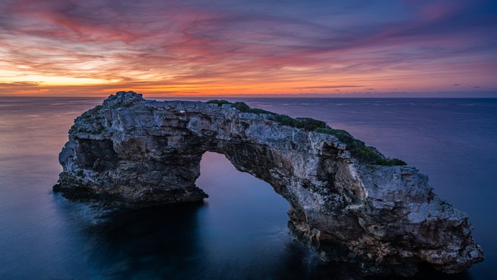 Natural rock arch over the sea at sunset in Mallorca