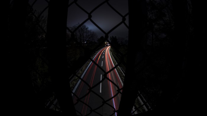 4K long exposure of a highway at night through a fence