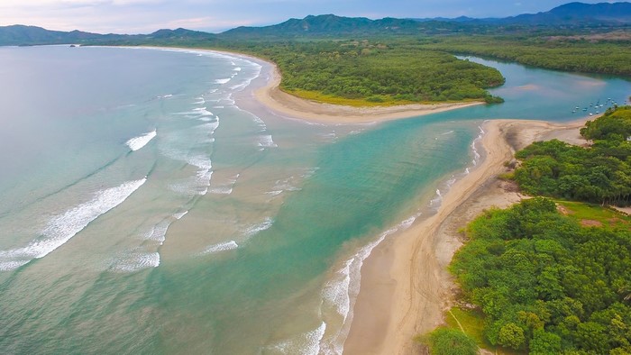 Aerial view of a tropical coastline with a river meeting the sea