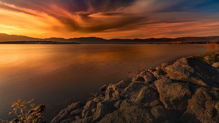 Sunset over a calm lake with mountains and rocks