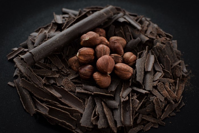 Chocolate shavings and hazelnuts on a dark surface