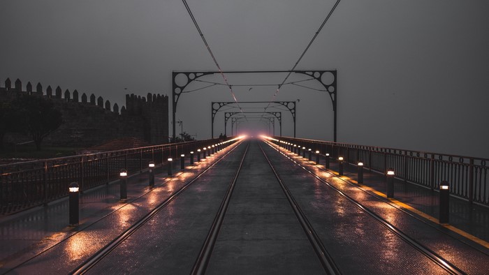 Empty bridge with tram tracks and lights at dusk