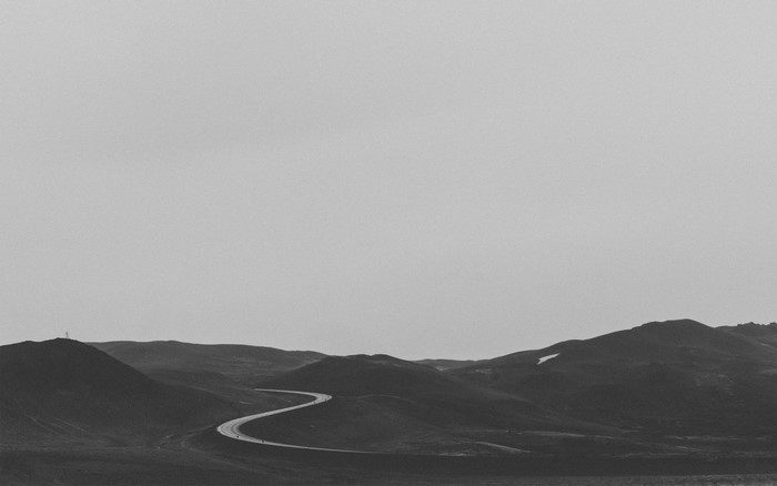 Winding road through rolling hills under a vast sky