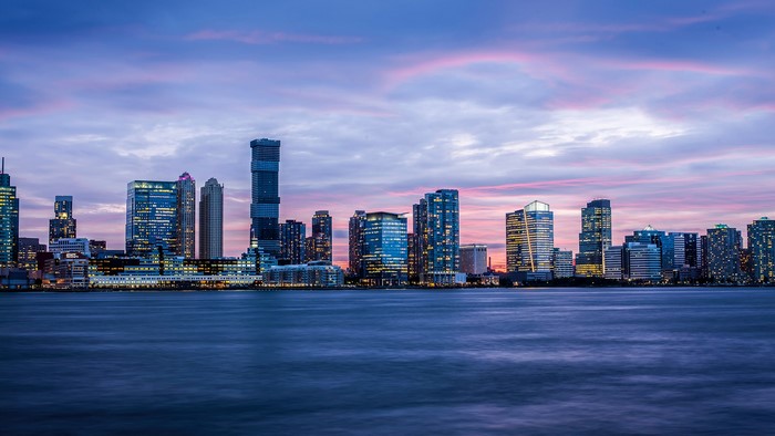City skyline at dusk with purple clouds and water
