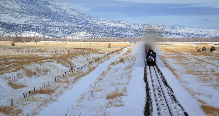 Train traveling through a snowy landscape with mountains