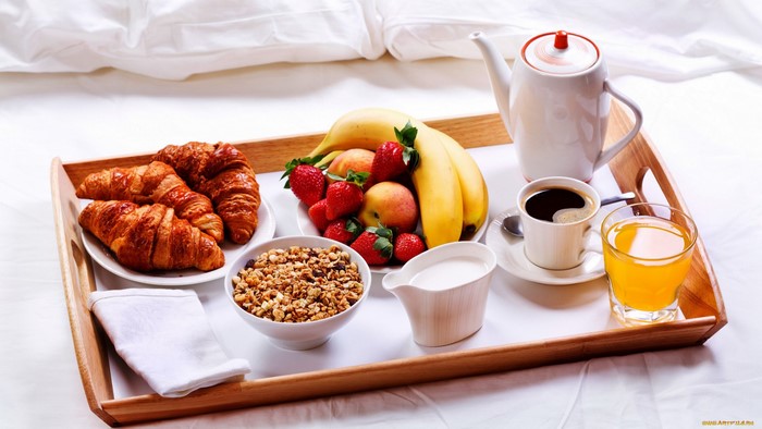 Breakfast tray with croissants, fruit, coffee, and juice