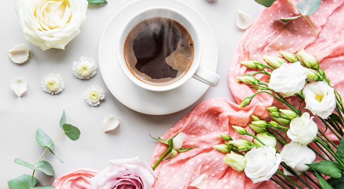Cup of coffee with flowers and pink fabric