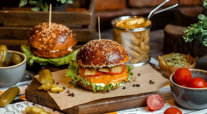 Two burgers with fries, pickles, and tomatoes