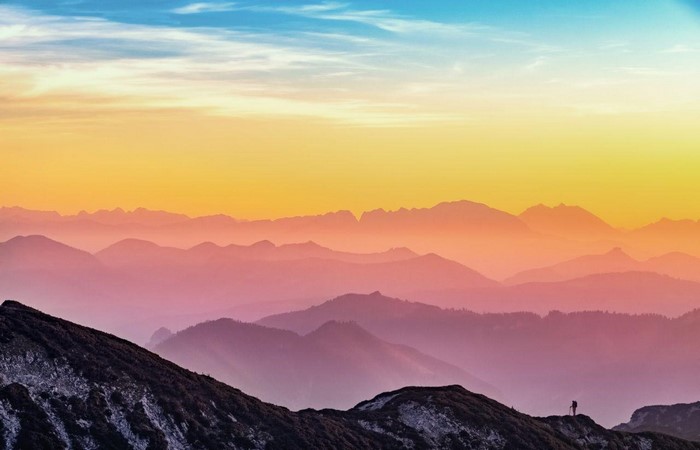 Mountain range at sunset with a lone hiker