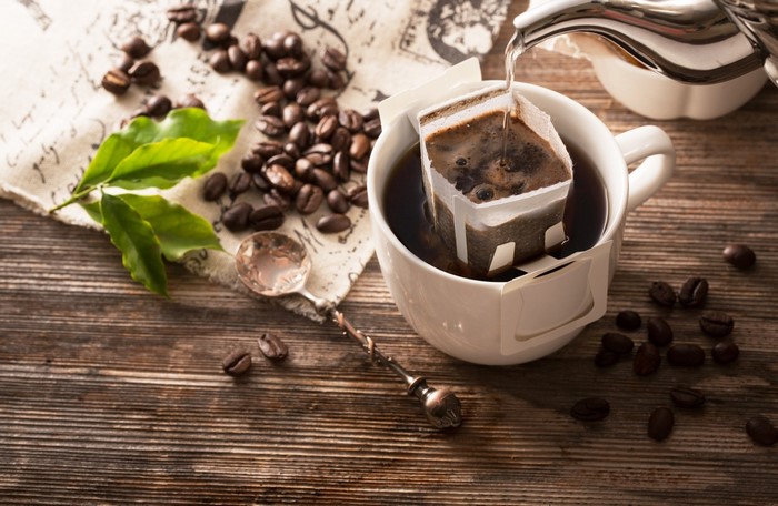 Pouring hot water into a drip coffee bag in a mug