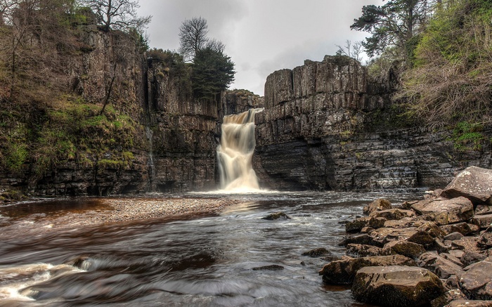 Waterfall cascading over rocky cliffs into a river