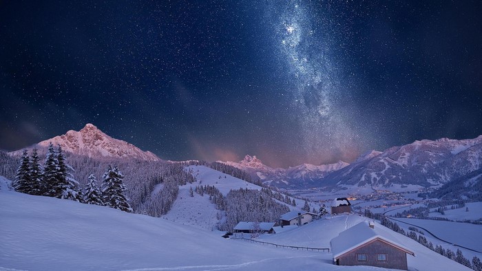 Milky Way over snow-covered mountains and forest