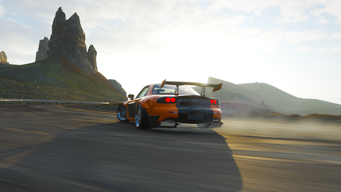 Orange Mazda RX-7 FD drifting on a road at sunset