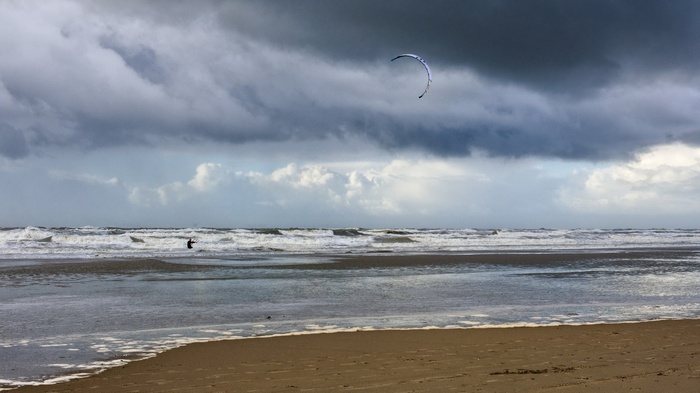 Kitesurfer on a stormy beach with waves