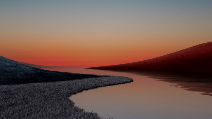 Sunset over a calm river with grassy hills