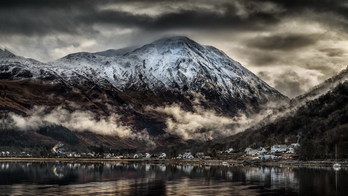 Snow-capped mountains over a village by a lake in Scotland