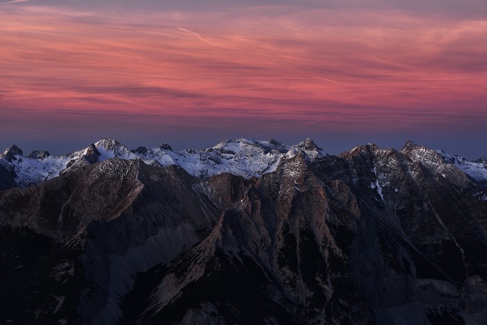Snowy mountain range at sunset with red sky