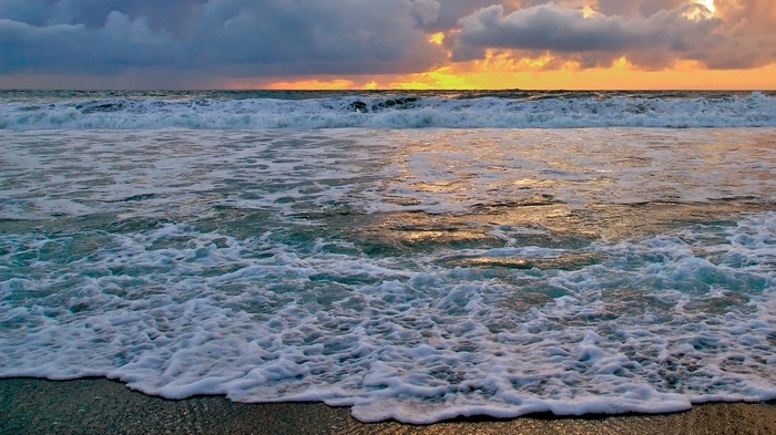 Ocean waves crashing on a beach at sunset