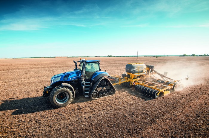 Blue tractor with planter in a dry field