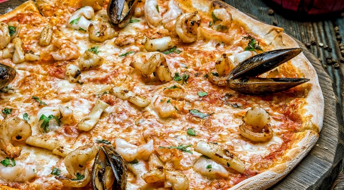 Seafood pizza with mussels and shrimp on a wooden surface