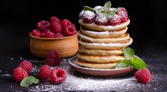 Stack of pancakes with raspberries and powdered sugar