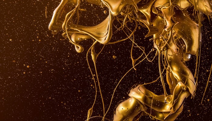 Abstract gold liquid splatter on dark background