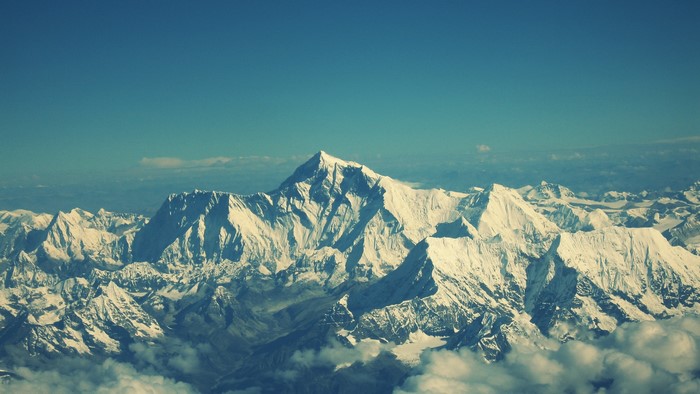 Mount Everest and surrounding snow-capped mountains under a blue sky