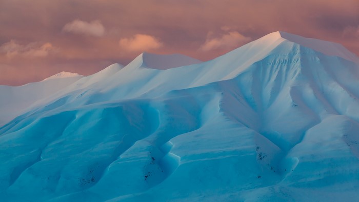 Snowy mountains at sunset with pink clouds