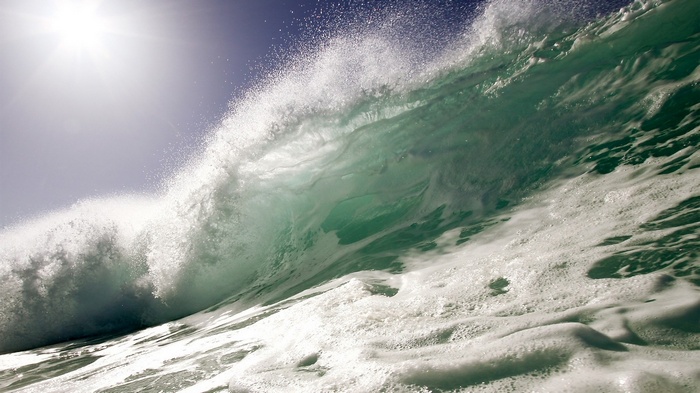 Crashing ocean wave with sun glare