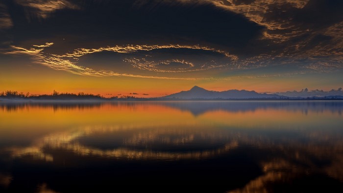 Sunset over a lake with mountains and reflection