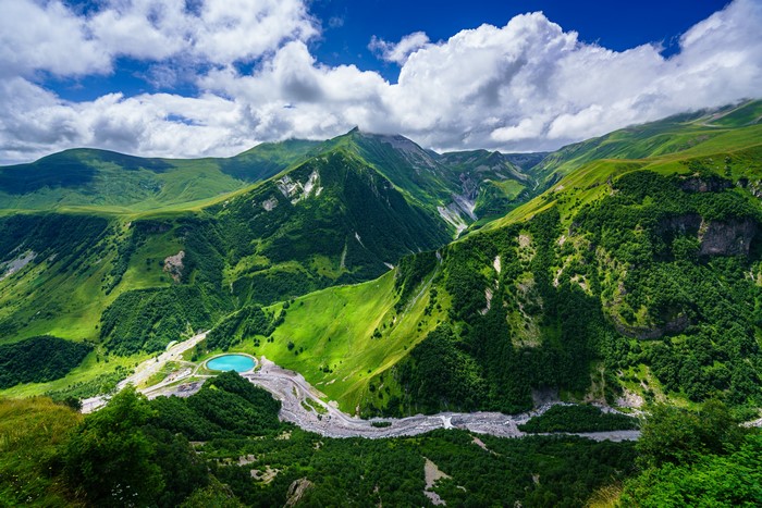 Green mountains with a lake and river under clouds